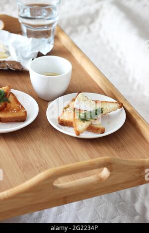Petit déjeuner au lit. Café du matin et toasts au fromage servis sur un plateau en bois. Petit déjeuner maison. Banque D'Images