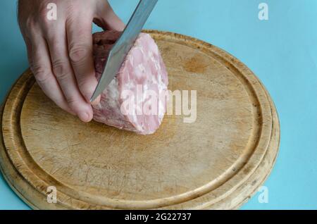 Jambon maison authentique, coupé en tranches à la main, à l'ail, au sel et au poivre noir. Couteau et jambon de porc appétissant sans tubage sur une planche à découper en bois. R Banque D'Images