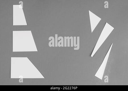 Formes géométriques blanches aléatoires sur gris. Trapèzes et triangles. Vue de dessus. Copier l'espace Banque D'Images