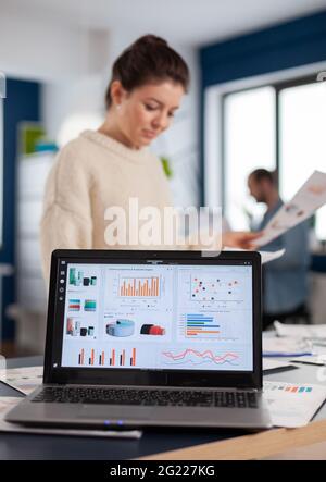 Ordinateur portable avec tableaux financiers sur le bureau de la start-up entreprise. Entrepreneur exécutif, chef d'équipe cadre travaillant sur des projets avec divers collègues. Statistiques en ligne d'entrepreneur professionnel réussi d'entreprise Banque D'Images