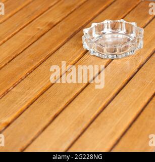 Cendrier en verre transparent sur une table en bois. Banque D'Images