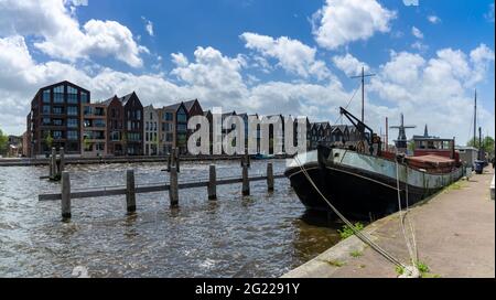 Haarlem, pays-Bas - 21 mai 2021 : rangée de maisons colorées sur les canaux de Haarlem avec une ancienne barge fluviale au premier plan Banque D'Images