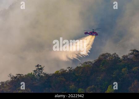 Un hélicoptère de lutte contre le feu qui larde de l'eau sur un feu de forêt Banque D'Images