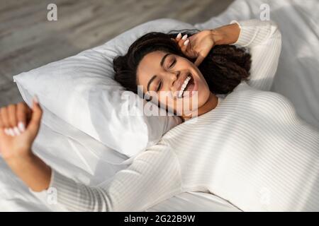 Bonne dame afro-américaine qui s'étire après s'être réveillée Banque D'Images