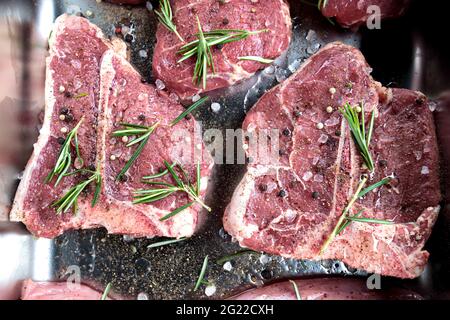 T os steak viande de veau crue. Bœuf Angus vieilli à base de os pour barbecue avec sel et assaisonnement au romarin. Bifteck frais coupé de boucher, noir gastronomique de qualité Banque D'Images