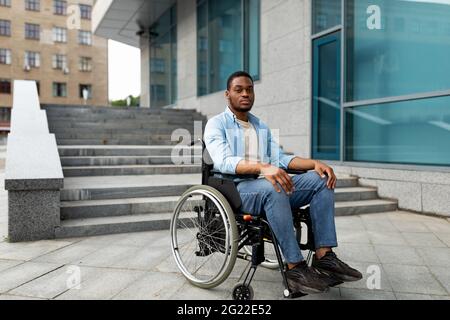 Portrait d'un malheureux homme noir malheureuse en fauteuil roulant à côté de siatrs sans rampe, se sentir stressé, espace libre Banque D'Images