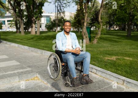 Concept d'environnement accessible aux personnes handicapées. Un bon homme noir en fauteuil roulant qui descend sur la rampe de la rue City Banque D'Images