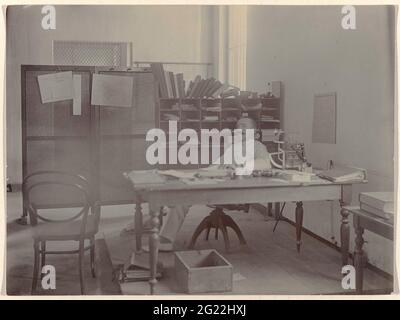 Homme derrière la table. Un homme assis derrière sa table de travail. Probablement un membre des rédacteurs du Deli courant à Medan. Sur un écran un calendrier avec le mois de septembre de l'année 1898. Partie d'un groupe de 8 photos de septembre 1898 dans le groupe de 49 photos en vrac noir et blanc de différents formats sur l'éditeur et l'impression du journal Deli courant à Medan dans la période 1885-1947. Banque D'Images