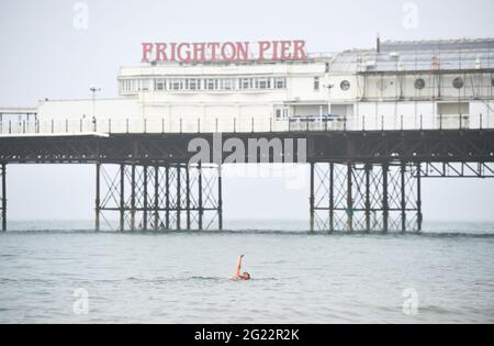 Brighton UK 8 juin 2021 - UN nageur dans la brume de mer par Brighton Palace Pier mais le soleil devrait le brûler d'ici l'après-midi avec des températures qui devraient atteindre le milieu des années 20 : crédit Simon Dack / Alamy Live News Banque D'Images