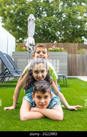 Portrait de trois enfants allongé sur une herbe Banque D'Images