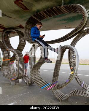 Enfants jouant sur un cadre d'escalade ou un banc sculptural (le plus long banc du Royaume-Uni) Banque D'Images