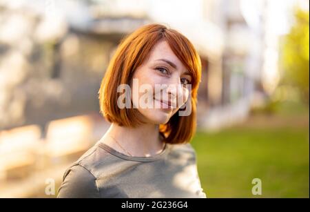 Portrait d'une femme souriante à la tête rouge dans la ville Banque D'Images