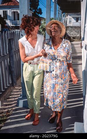 Une femme aveugle âgée de Belizean a aidé dans la rue par un travailleur humanitaire. Belize City, Belize, Amérique centrale Banque D'Images