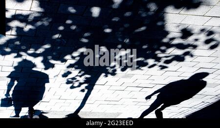 Silhouette d'ombre floue de deux personnes debout seules sous un arbre sur un trottoir de rue de ville, en noir et blanc Banque D'Images