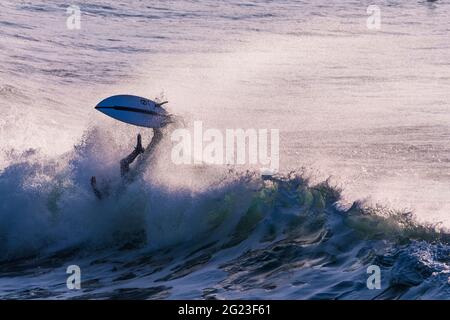 Un surfeur s'enfuyant sur une vague sauvage à Fistral à Newquay, en Cornouailles. Banque D'Images