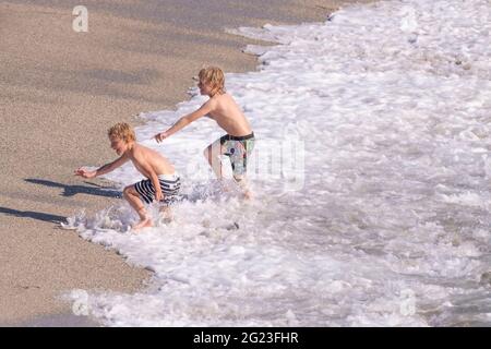 Deux jeunes garçons enthousiastes jouant dans la mer sur Little Fistral Beach à Newquay, en Cornouailles. Banque D'Images