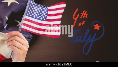 Joyeux texte du jour de l'indépendance et main tenant un drapeau américain contre nous drapeau sur fond de bois Banque D'Images