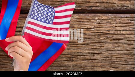 Main tenant un drapeau américain contre le ruban rouge sur une surface en bois Banque D'Images