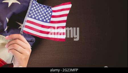 Main tenant un drapeau américain contre notre drapeau sur une surface en bois Banque D'Images