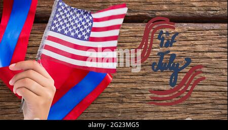 Texte et main heureux jour de l'indépendance tenant un drapeau américain sur fond de bois Banque D'Images