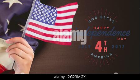 Joyeux texte du jour de l'indépendance et main tenant un drapeau américain contre nous drapeau sur fond de bois Banque D'Images
