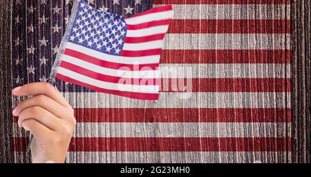 Main tenant un drapeau américain contre nous drapeau sur fond de bois Banque D'Images