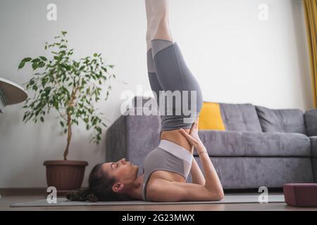 Vue latérale de la femme flexible dans les vêtements de sport faisant posture de l'épaule Banque D'Images