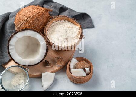 Farine de noix de coco et noix de coco sur fond gris. Vue latérale, espace de copie. Aliments biologiques sains. Banque D'Images