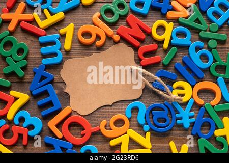 Étiquette en papier marron vierge avec alphabet en plastique coloré sur fond en bois Banque D'Images