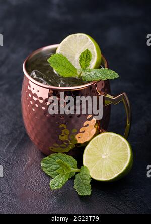 Moscovite mule cocktail dans un mug en cuivre avec citron vert et menthe sur fond de table de cuisine sombre Banque D'Images
