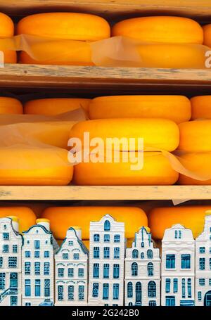 Le fromage hollandais mûrit sur des étagères en bois avec des maisons de souvenirs Delft devant Banque D'Images