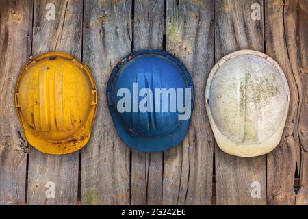 Trois casques de construction vintage suspendus sur un vieux mur en bois Banque D'Images