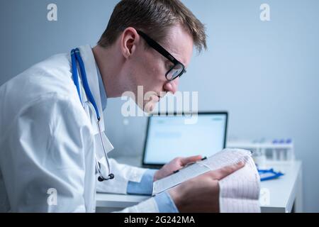 Sujet de la vérification rapide de la maladie cardiaque. Maladie cardiaque infarctus du myocarde. Médecin analysant l'électrocardiogramme au bureau de l'hôpital Banque D'Images