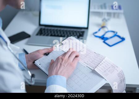 Sujet de la vérification rapide de la maladie cardiaque. Maladie cardiaque infarctus du myocarde. Médecin analysant l'électrocardiogramme au bureau de l'hôpital Banque D'Images