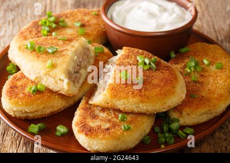 Crêpes de pommes de terre Zrazy avec garniture de viande à la crème aigre gros plan dans une assiette sur la table. Horizontale Banque D'Images
