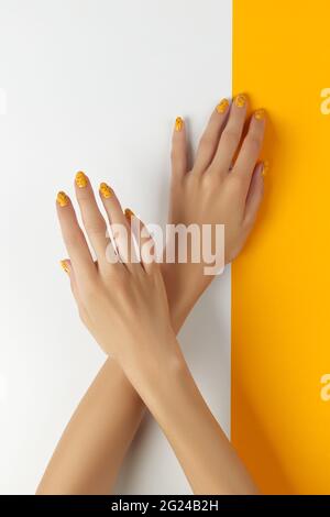 Femmes manucures avec un motif à ongles tendance sur fond orange Banque D'Images
