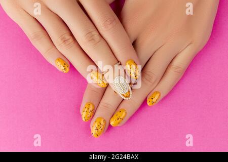Femmes manucures avec un motif à ongles tendance sur fond rose Banque D'Images