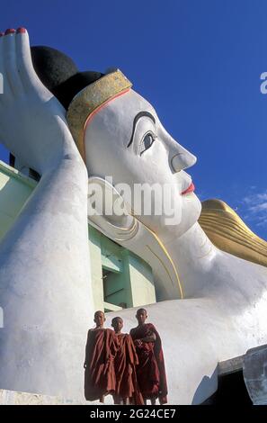 Myanmar, Monyma, Division Mandalay, moines novice debout sous la statue géante du Bouddha couché dans le temple Lay Kyune Sakkyar Banque D'Images