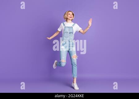 Photo pleine grandeur de beau optimiste court coiffure blonde dame saut porter blanc t-shirt ensemble isolé sur fond violet Banque D'Images