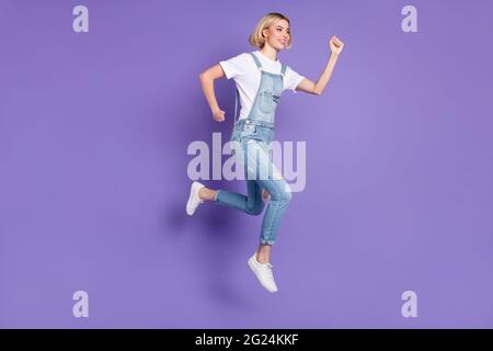 Pleine taille profil photo de beau optimiste court coiffure blonde femme courir vêtements blanc t-shirt général isolé sur fond violet Banque D'Images