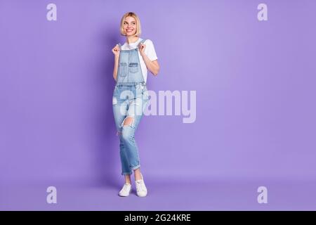 Pleine taille photo de beau optimiste court coiffure blonde dame look vide espace porter t-shirt blanc ensemble isolé sur fond violet Banque D'Images