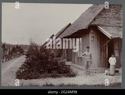 Bâtiments à Bivac Lampahan. Bâtiments du Bivouac Lampahan, officier avec une femme à l'intérieur des terres devant une maison. Photos empilées dans un album avec 87 photos sur la construction du Gajoegweg sur le nord de Sumatra entre Bireuen et Takenuen entre 1903 et 1914. Banque D'Images