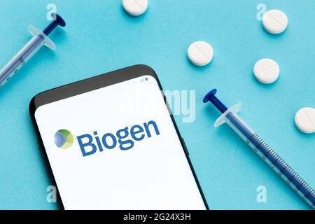Galice, Espagne; 8 juin 2020 : smartphone montrant le logo Biogen à l'écran et les pilules et la seringue sur fond bleu Banque D'Images