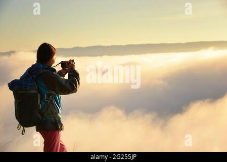 Silhouette d'une femme debout sur une montagne au-dessus d'un tapis de nuages avec ses bras étirés, Thaïlande Banque D'Images