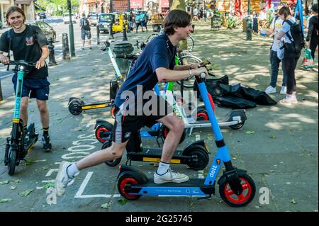 Londres, Royaume-Uni. 8 juin 2021. Beaucoup semblent trouver le processus de déverrouillage assez difficile, mais une fois qu'ils se mettent en marche, ils semblent assez heureux - les scooters électriques (e-scooters) sont maintenant disponibles à louer dans un petit nombre de quartiers de Londres. C'est la seule façon de conduire légalement un e-scooter sur la voie publique ou dans d'autres lieux publics de Londres. La location de trottinettes électroniques est assurée par trois opérateurs différents : Dott, Lime et TIER. Pour louer un e-trottinette, les utilisateurs doivent : télécharger l'application de l'opérateur choisi, terminer le processus d'inscription, y compris vérifier votre âge et votre permis de conduire, et remplir la commande Banque D'Images