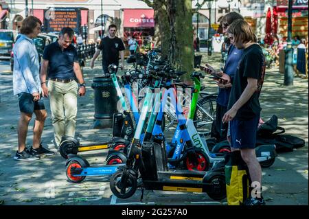 Londres, Royaume-Uni. 8 juin 2021. Beaucoup semblent trouver le processus de déverrouillage assez difficile, mais une fois qu'ils se mettent en marche, ils semblent assez heureux - les scooters électriques (e-scooters) sont maintenant disponibles à louer dans un petit nombre de quartiers de Londres. C'est la seule façon de conduire légalement un e-scooter sur la voie publique ou dans d'autres lieux publics de Londres. La location de trottinettes électroniques est assurée par trois opérateurs différents : Dott, Lime et TIER. Pour louer un e-trottinette, les utilisateurs doivent : télécharger l'application de l'opérateur choisi, terminer le processus d'inscription, y compris vérifier votre âge et votre permis de conduire, et remplir la commande Banque D'Images