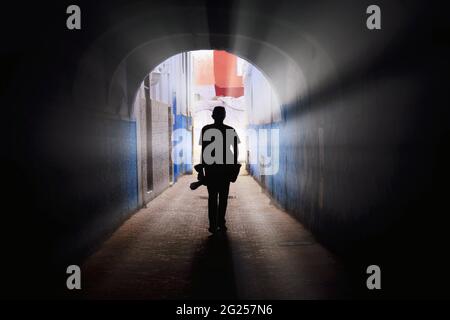 Silhouette d'homme avec une caméra traversant un tunnel à Chefchaouen, Maroc Banque D'Images