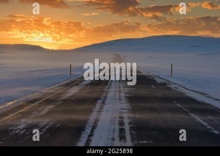 Route 1 périphérique à travers le paysage hivernal enneigé au coucher du soleil, en Islande Banque D'Images