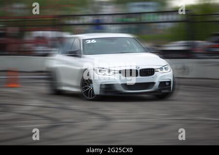 KIEV-15 MAI,2021: BMW M3 blanc F80 course de voiture de sport sur la piste de dérive avec effet de mouvement flou sur la dérive et les voitures d'exposition. Véhicule allemand hautes performances Banque D'Images