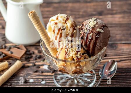 Glace Roma au chocolat, à la crème et au caramel dans un bol en verre avec une sauce au chocolat et aux noisettes. Banque D'Images